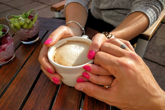 マグカップを持つ女性の手を握る男性の手