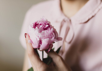 ピンクの花を一輪持っている女性