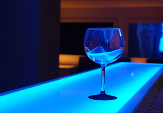 青いライトのバーカウンターでグラスが一つ
