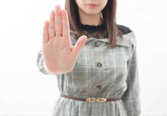 女性が手のひらを翳して近寄るなポーズをしている