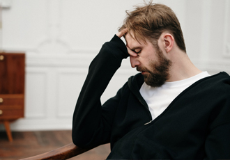 男性が額に手を置いて落ち込んでいる